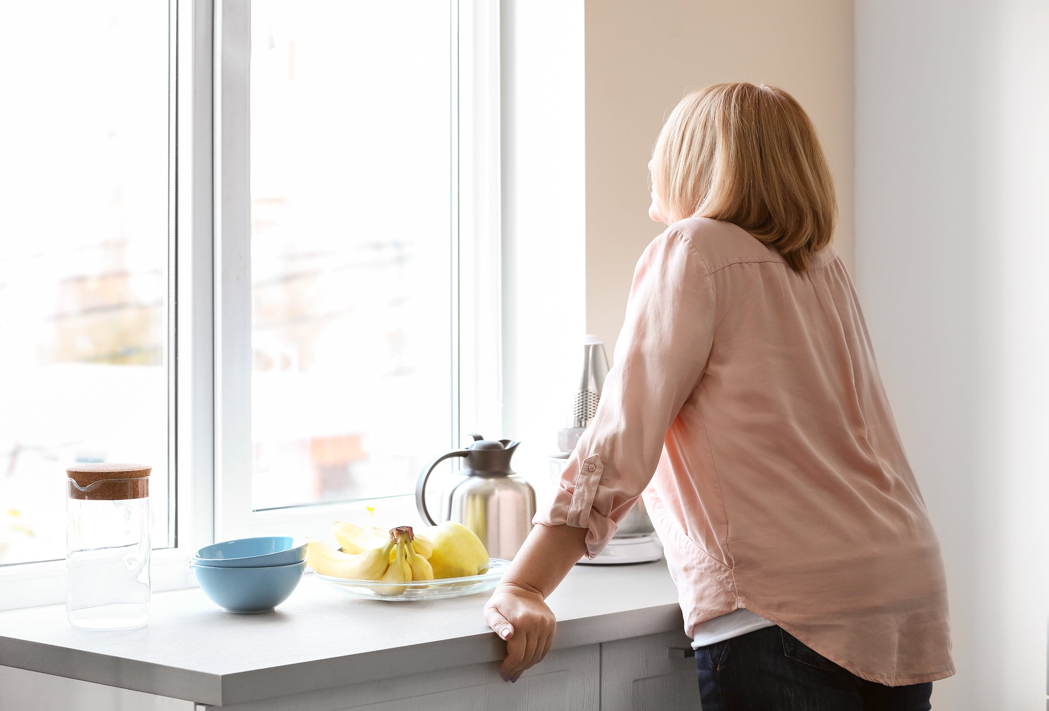 Traurige Frau, mit dem Gesicht zum Fenster und dem Rücken zur Kamera