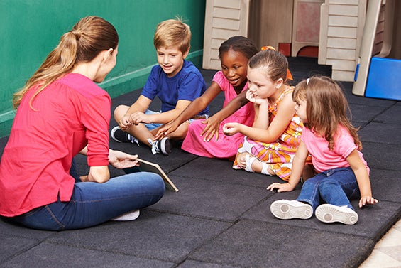 Gruppe Kinder redet über ein Buch im Kindergarten mit der Erzieherin