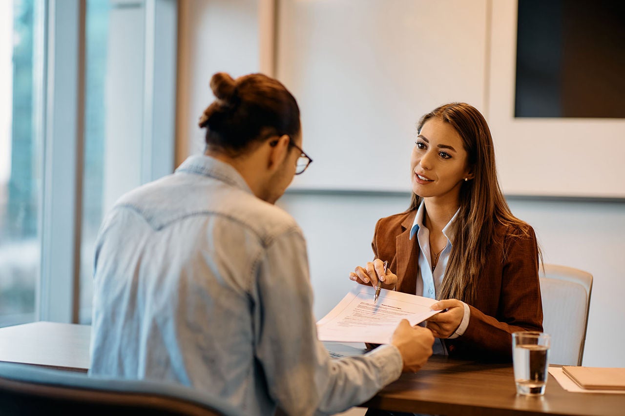 Young bank manager going through agreement with her client during meeting in office., Young bank manager going through agreement with her client durin
