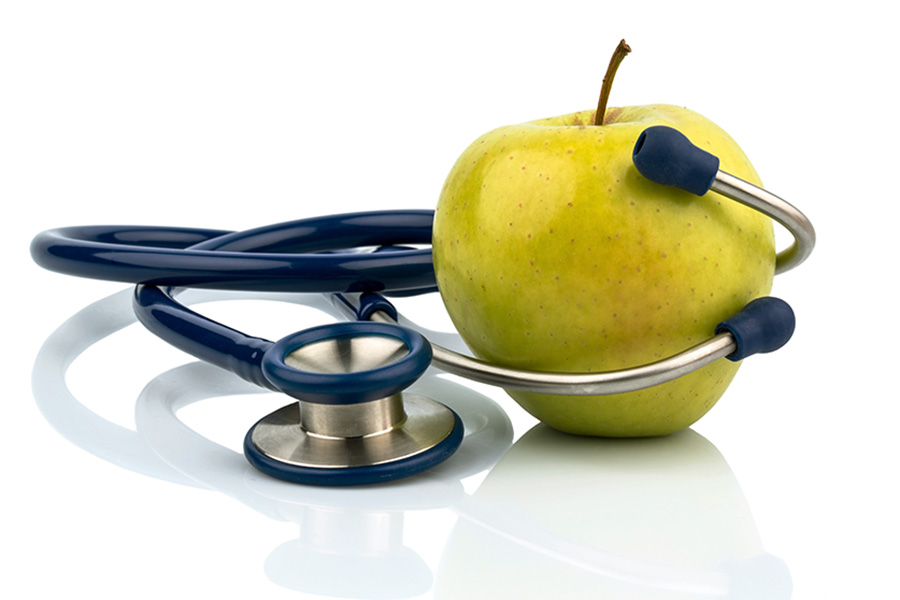 Ein Apfel und ein Stethoskop bei einem Arzt. Symbolfoto fÃ¼r gesunde und vitaminreiche ErnÃ¤hrung.