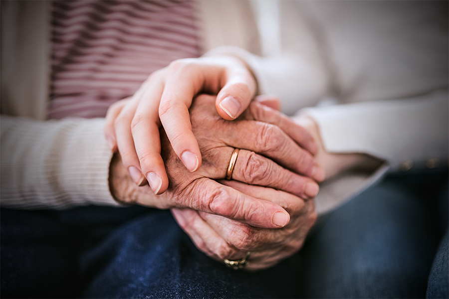 Pflegerin hält Hände einer Patientin