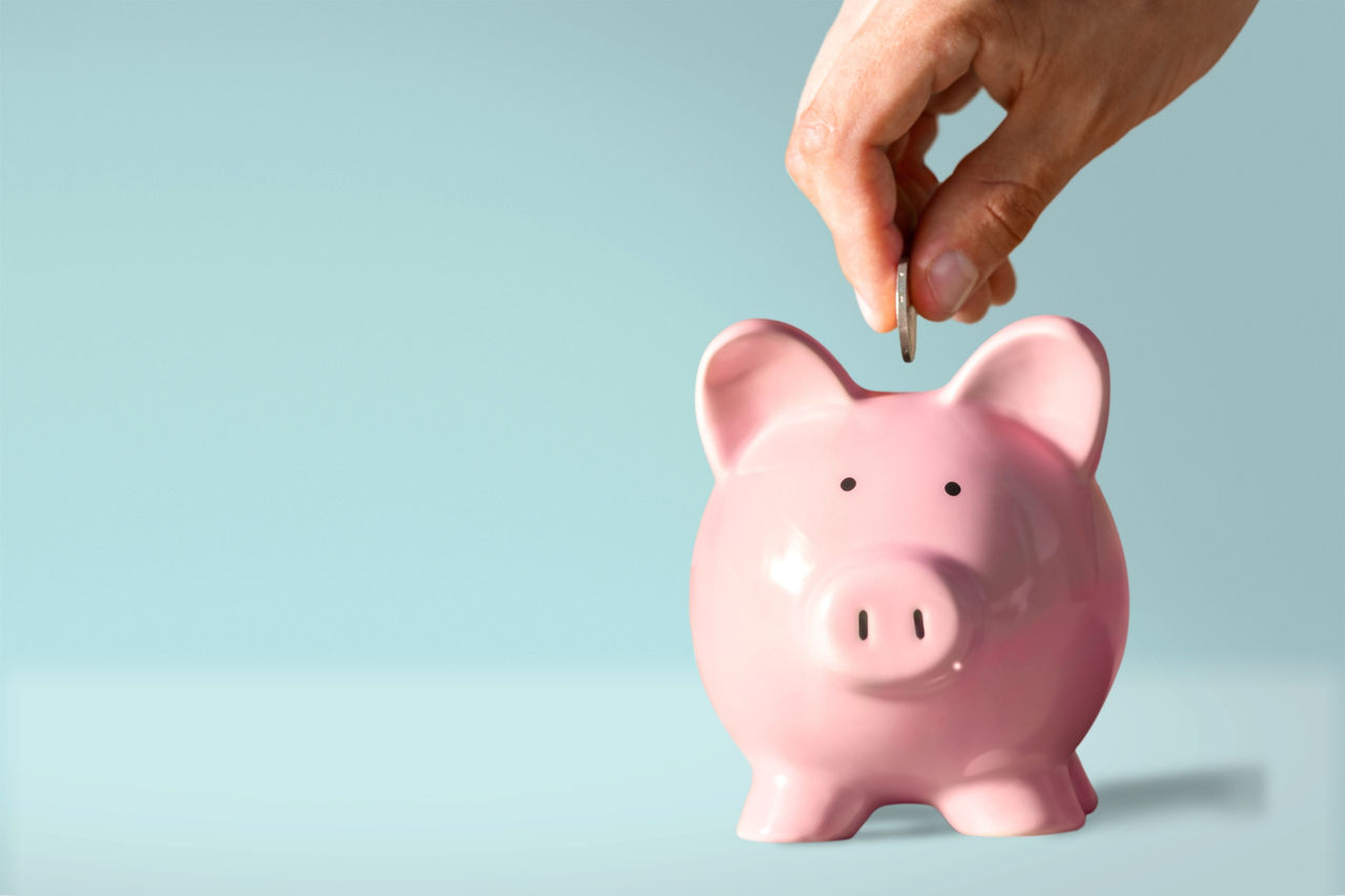 Female hand putting coin into piggy bank closeup